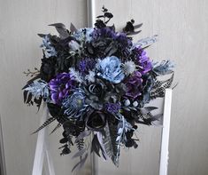 a bridal bouquet with blue and purple flowers on a white chair in front of a door