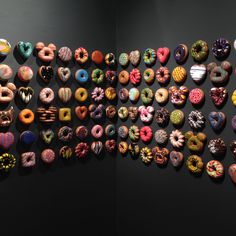 several different types of donuts on display in a museum exhibit area with black walls