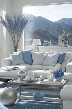 a living room filled with white furniture and blue pillows on top of it's couches