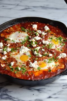 an egg dish in a skillet on a marble counter top with other food items