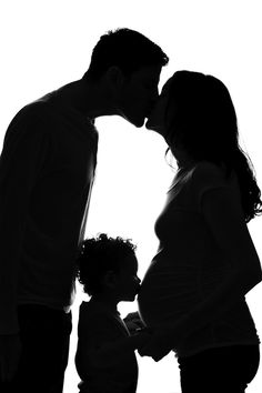 a man and woman kissing while standing next to a baby in front of a white background