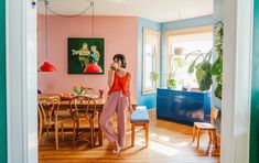 a woman standing in the doorway of a pink and blue dining room