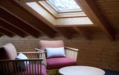 two chairs and a table in a room with wood paneling on the walls, one has a skylight above it