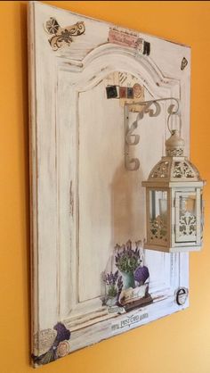 an old white door with a lantern hanging on it's side and some flowers