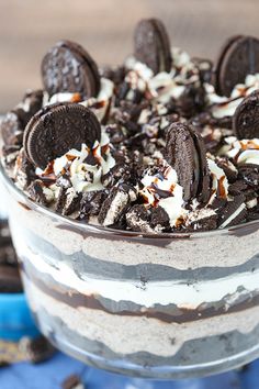 an oreo cookie and cream trifle in a glass dish on a blue cloth