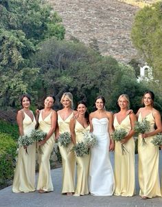 a group of women standing next to each other in front of some trees and bushes