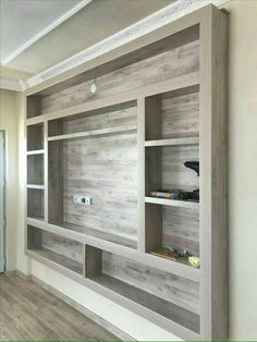 an empty room with wooden shelves and wood flooring on the walls, in front of a white painted wall