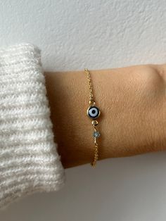 Brush away negative energy and jealous prying eyes with this dainty evil eye bracelet that you can customise by adding the gemstone/birthstone of your choice. D E T A I L S *It features a gold filled evil eye charm (12 x 6.5mm) in traditional blue *on an 18k gold filled chain in yellow gold.  *Gold fill or gold filled is an amazing quality alternative to solid gold. Unlike gold plating that over time tends to tarnish, gold filled is an actual layer of gold, pressure- bonded to another metal and with the proper care can last for years. *Add the gemstone of your choice. These are high quality crystals measuring between 3 and 4mm.  *Length: Choose the length you prefer from the drop down menu. A snug fit works best for the bracelet so use the length chart as a reference. *Bracelet comes with Spiritual Crystal Bracelet With Evil Eye, Spiritual Crystal Bracelet With Evil Eye For Gift, Dainty Evil Eye Bracelet With Adjustable Chain, Minimalist Beaded Bracelet With Evil Eye For Gift, Minimalist Evil Eye Beaded Bracelets As Gift, Minimalist Evil Eye Bracelet With Adjustable Chain As Gift, Dainty Evil Eye Bracelet Jewelry, Minimalist Round Evil Eye Bracelet, Dainty Evil Eye Bracelet For Everyday Wear