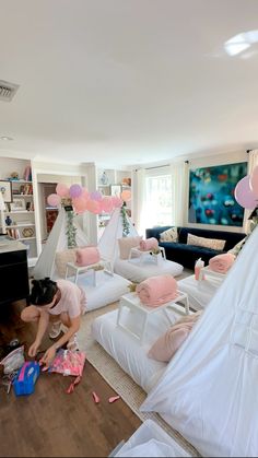 a woman is decorating some white couches in a living room with pink decorations