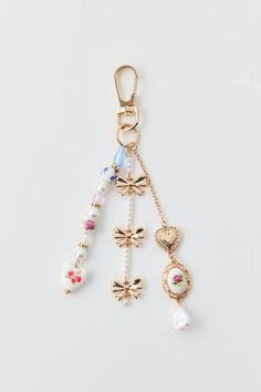 a key chain with charms attached to it on a white surface, one is gold and the other is multicolored