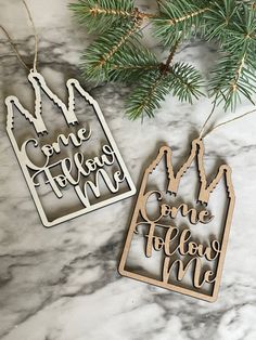 two christmas ornament hanging from a pine tree on a marble surface with the words, one belongs me and some belong me