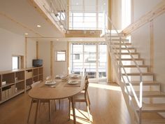 a dining room table and stairs leading to the upper floor in a modern home with wood floors