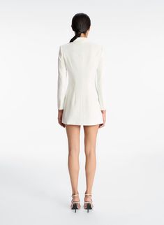 The Juliet Dress is crafted from our signature suiting fabric in bridal white. This mini blazer silhouette features modern twists on classic tuxedo-inspired details, including pointed notch lapels, a faux-wrap waist, flap pockets, and an asymmetrically pleated skirt. Shop Dresses Styling Tip: ﻿Pair yours with white or metallic high-heeled sandals for your rehearsal dinner or engagement party. White Fitted Dress With Notch Lapel, White Notch Lapel Fitted Dress, White Fitted Structured Blazer, Tailored Long Sleeve Blazer Dress For Wedding, Elegant Tailored Mini-length Blazer, Elegant Notch Lapel Blazer Dress For Cocktail, Elegant White Blazer Dress With Hidden Buttons, Elegant Fitted Blazer Dress For Wedding, Tailored Blazer Dress With Notch Lapel For Cocktail