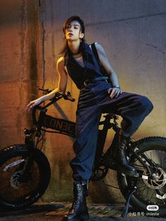 a woman sitting on top of a bike next to a wall