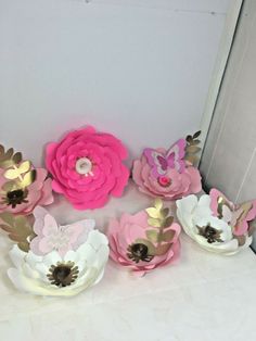 pink and white paper flowers sitting on top of a table