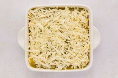 a casserole dish with grated cheese in it on a white table top