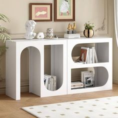 a white book shelf with books on it in a living room next to a potted plant