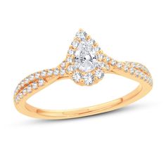 a gold engagement ring with a pear shaped diamond center and pave set diamonds on the band