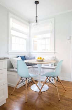 a kitchen table with four chairs and a bowl of fruit on the table in front of it