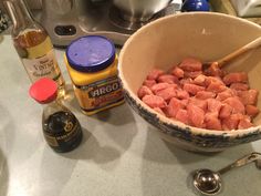 a bowl filled with diced meat sitting on top of a counter next to a bottle of mustard