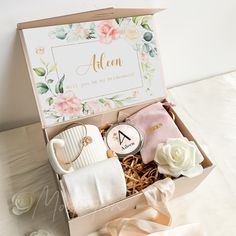 an open box with personalized items in it on a table next to some flowers