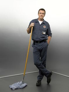 a man holding a broom standing on top of a floor