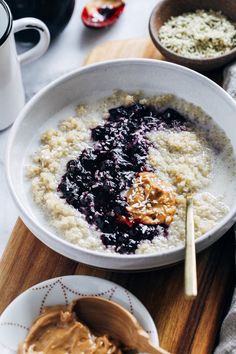 a bowl of oatmeal with blueberries and peanut butter on the side