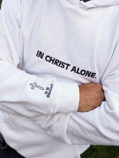 "See store for Christmas deadlines!Introducing the perfect addition to your wardrobe - the Gildan 18500 embroidered with \"In Christ Alone\" across the chest and adorned with a beautifully embroidered cross finished on the arm. This high-quality, comfortable shirt is perfect for both men and women and is made from a durable blend of cotton and polyester. The embroidered design adds a touch of elegance and meaning to the shirt, making it perfect for those who want to express their faith in a styl White Hoodie With Custom Embroidery, White Long Sleeve Hoodie With Custom Embroidery, Cotton Hoodie With Embroidered Text And Long Sleeves, Cotton Hoodie With Embroidered Graphics, Long Sleeve Cotton Hoodie With Embroidered Text, Cotton Long Sleeve Hoodie With Embroidered Text, Embroidered Relaxed Fit Long Sleeve Hoodie, White Long Sleeve Hoodie With Embroidered Graphics, White Hoodie With Embroidered Graphics In Relaxed Fit