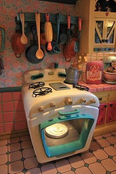 an old fashioned stove in a kitchen with pots and pans hanging on the wall