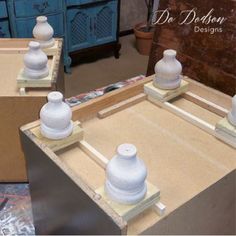 three white vases sitting on top of a wooden table in front of a mirror