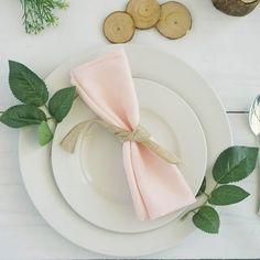 a place setting with pink napkins and greenery