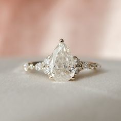 a close up view of a ring with a pear shaped diamond on it's side