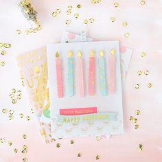 three birthday candles on top of each other with gold confetti around the edges