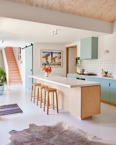 a kitchen with blue cabinets and wooden stools next to an island in the middle