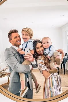 a man and woman taking a selfie with their children in front of a mirror