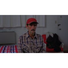 a man with a red hat and glasses sitting on a bed