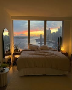 a bedroom with a large window overlooking the water and cityscape in the background