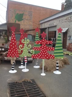 several christmas trees are on display in front of an old truck and other junk yard decorations