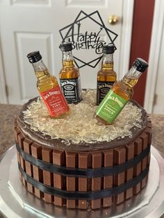 a chocolate cake with three bottles of whiskey on top and coconut flakes around it