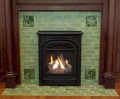 a fireplace with green tiles and wood trimming