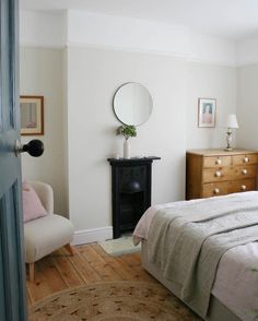 a bedroom with a bed, dresser and chair in it's corner area next to a mirror