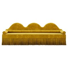 a yellow couch with long fringes on it's back and arms, sitting in front of a white background