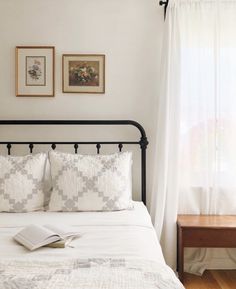 a bed with white sheets and pillows next to a window