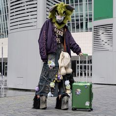 a man in a lion mask is standing next to a suitcase and holding a stuffed animal