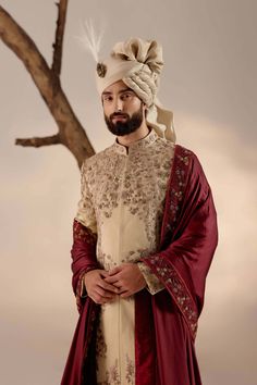 a man with a turban standing in front of a tree wearing a red and white outfit