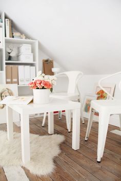 there is a white table with flowers on it in the room next to some bookshelves