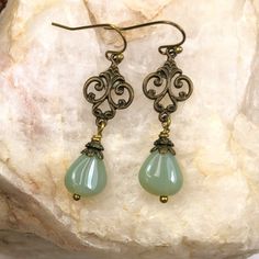 Teardrop beads in opalescent sage green dange from brass filigree.  The intricate filigree charm adds an elegant touch to these green  earrings. High quality Czech glass beads. Trendy green earrings that go with so many colors and styles this season, you'll want this color in your jewelry collection.  Custom earrings: other color beads and metals available.  Bridesmaid earrings can be made in mulitples. Convo me via Etsy with your ideas. Free gift packaging included. Earrings are carded and in an organza bag. Choose your ear wire style at checkout. Hypoallergenic ear wires (nickel and lead free).  Artisan glass beads produced in small quantities in the Czech Republic. Link back to my shop: https://www.etsy.com/shop/JezaJewelry Green Earrings - Teardrop Dangle Glass Beads - Handmade Gift - Nickel-free Czech Glass Teardrop Earrings As Gift, Czech Glass Teardrop Earrings Gift, Hypoallergenic Czech Glass Teardrop Jewelry, Vintage Teardrop Beaded Earrings Nickel Free, Nickel-free Teardrop Vintage Beaded Earrings, Nickel-free Vintage Teardrop Beaded Earrings, Elegant Jade Beaded Earrings With Round Beads, Elegant Jade Beaded Round Earrings, Elegant Hypoallergenic Teardrop Beaded Earrings