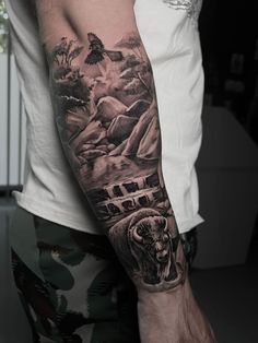 a man's arm with an animal and mountain scene tattoo on the left forearm