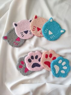 four hand towels with cat designs on them sitting on a white bed sheet in the shape of cats