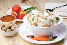 two bowls filled with rice, carrots and meatballs on top of a wooden table